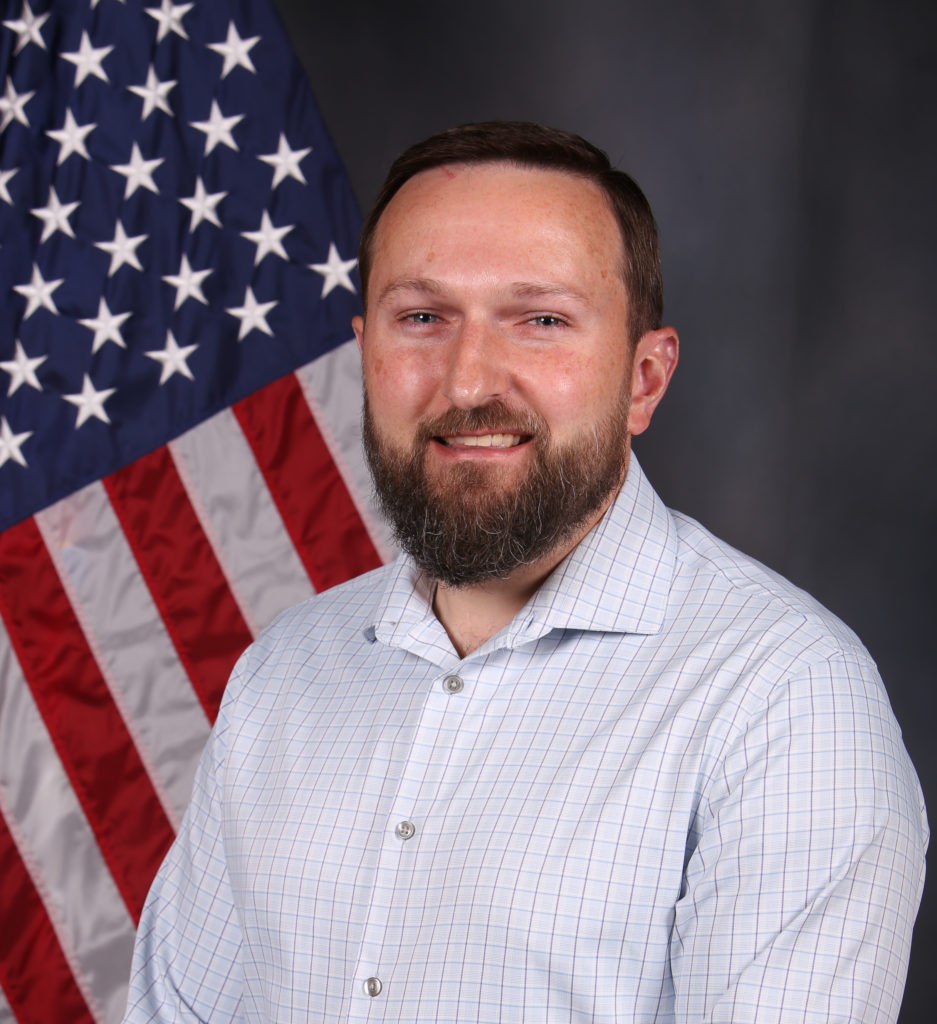 A man standing in front of a flag.