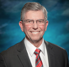 Chet D. Traylor wearing glasses and a suit.