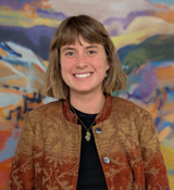 A man smiling in front of a colorful background.