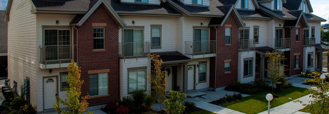 A large brick building with a lawn and trees in front of it.