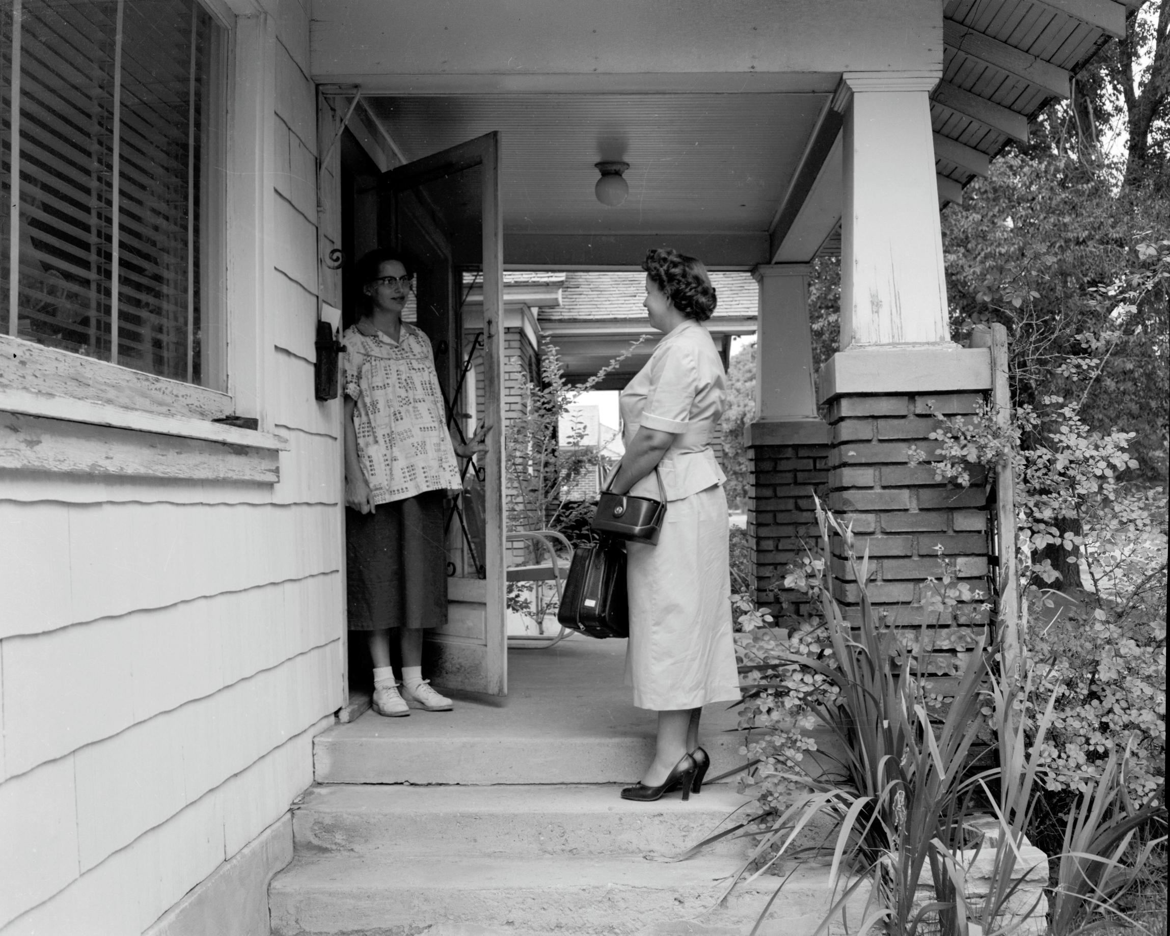 A couple of women standing outside a house.