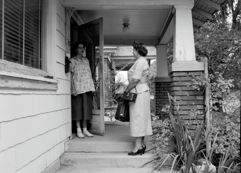 A couple of women standing outside a house.