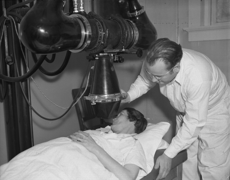 A woman looking at a man in a hospital bed.