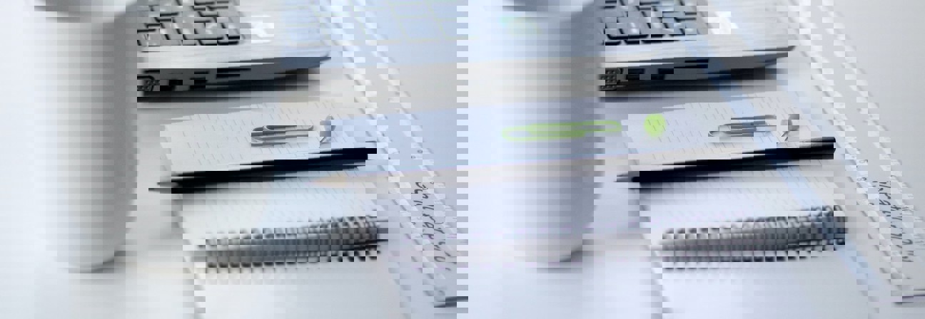 A stack of papers next to a laptop.