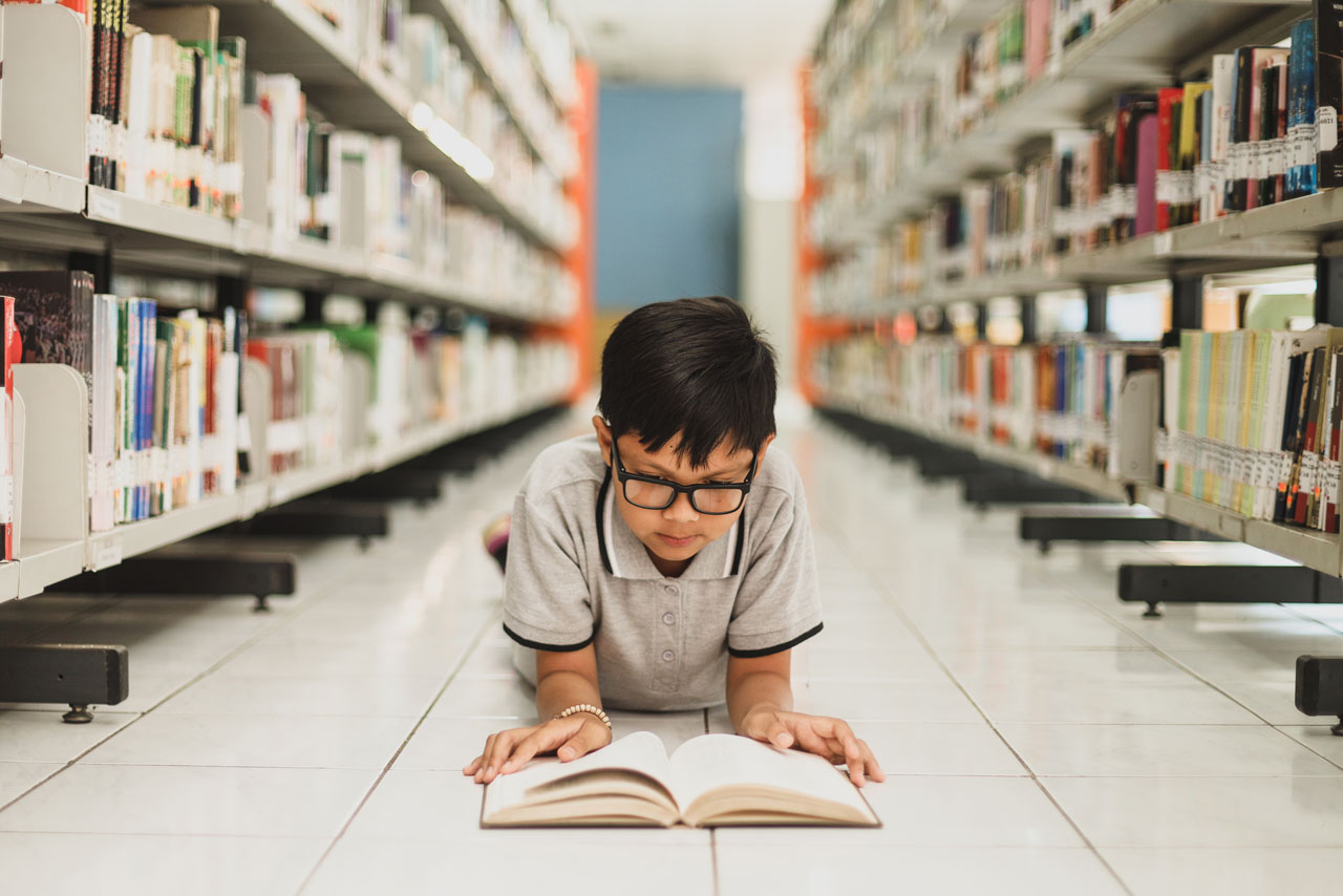 A person reading a book in a library.