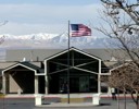 A flag on a pole in front of a building with mountains in the background.