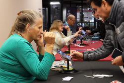 A group of people sitting at a table with a game controller.