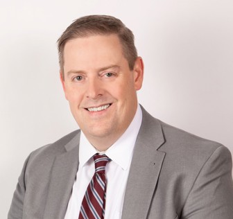 A man in a suit smiling.