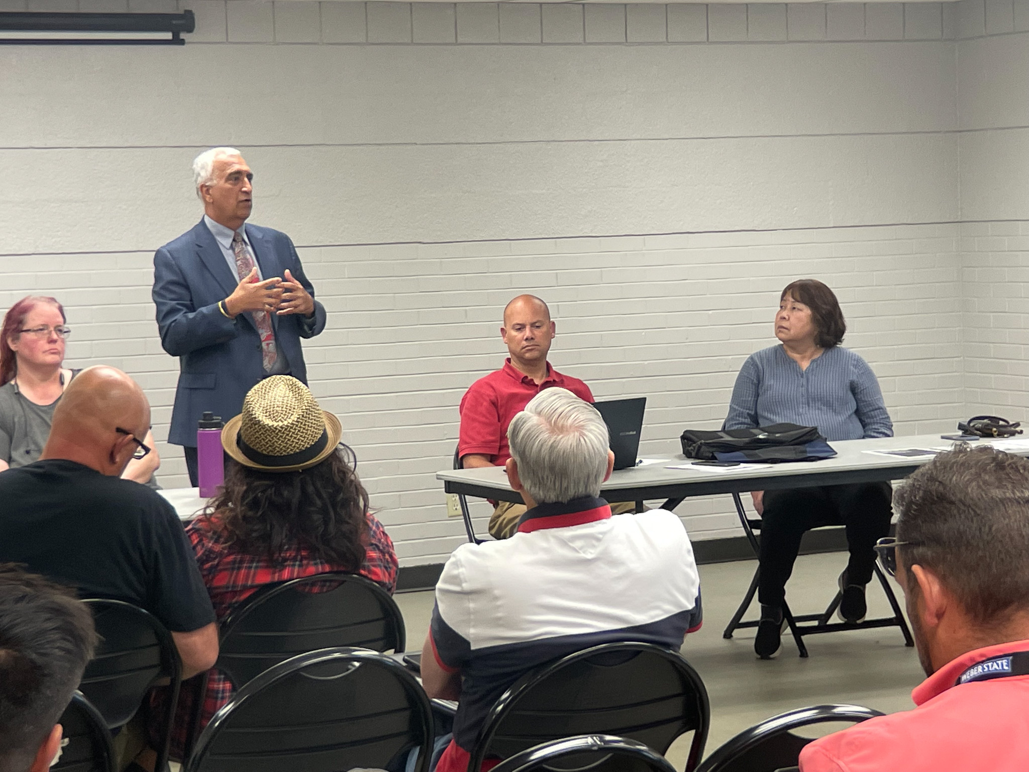 A man speaking to a group of people sitting at tables.