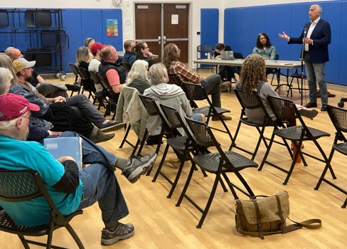A person standing in front of a group of people sitting in chairs.