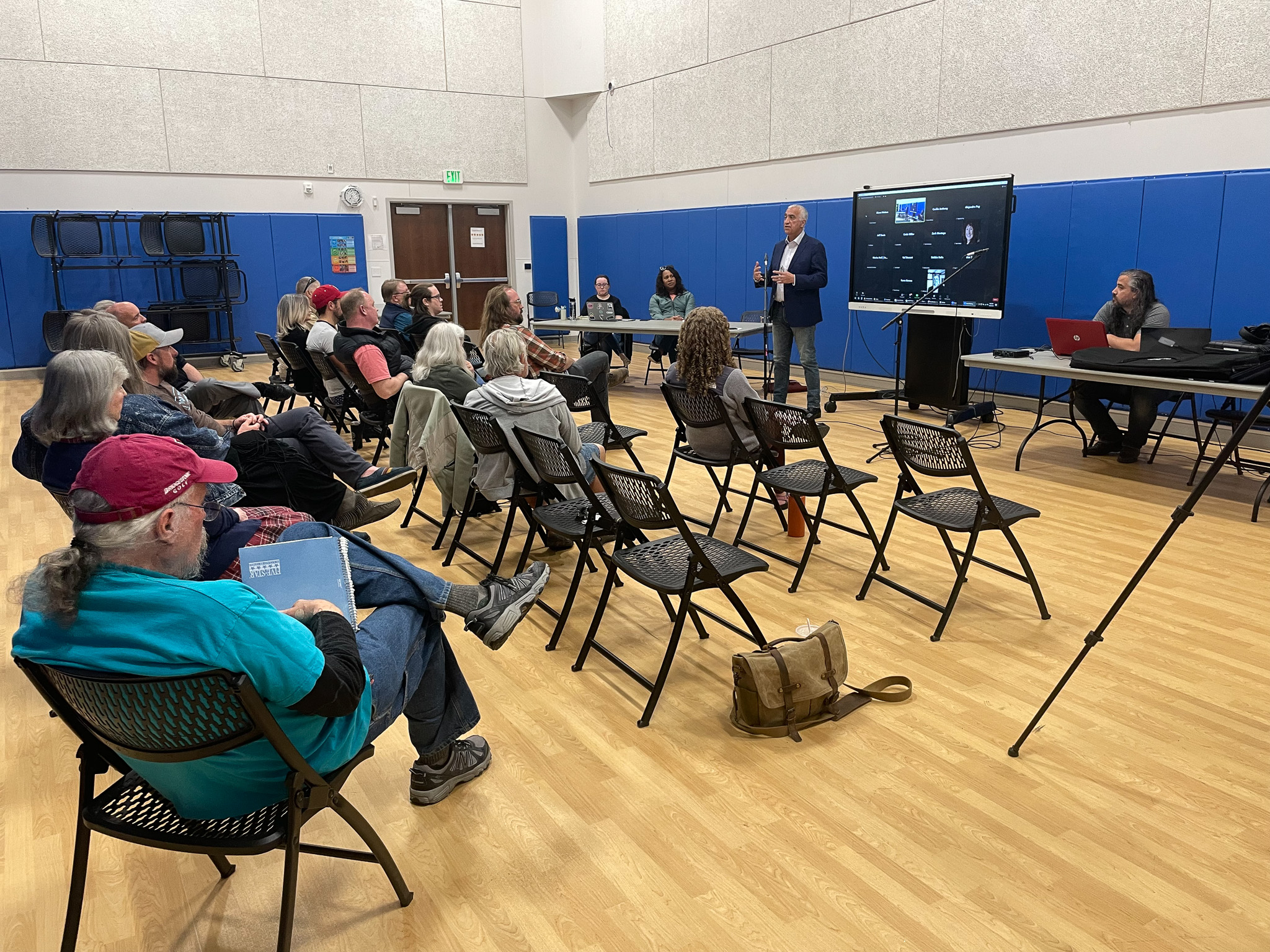 A group of people sitting in a room with a person standing in front of a screen.