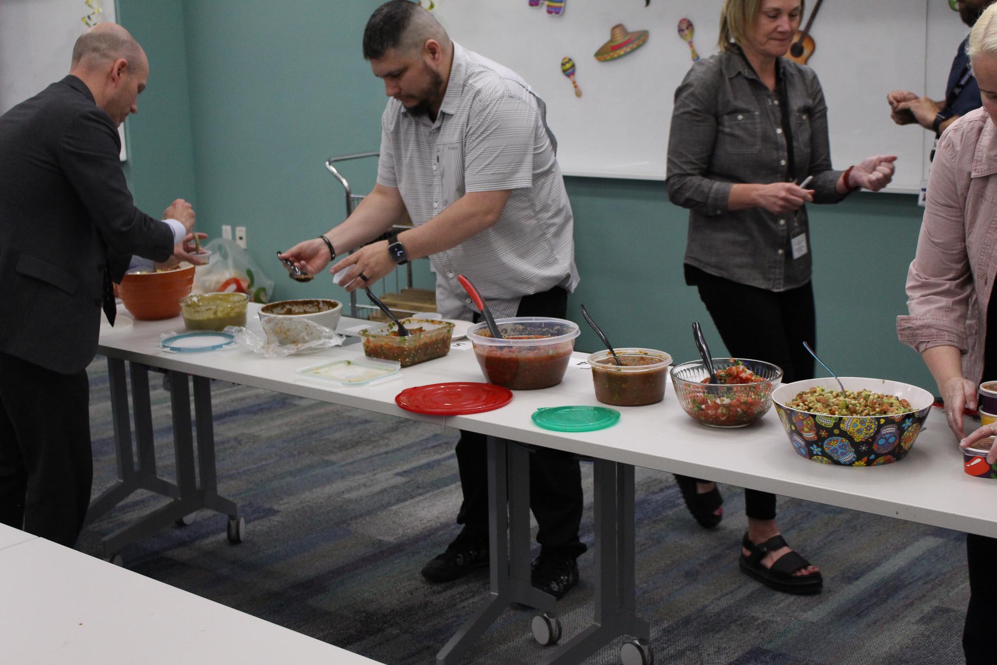 A group of people standing around a table with food on it.