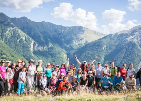 A group of people posing for a photo in front of a mountain.