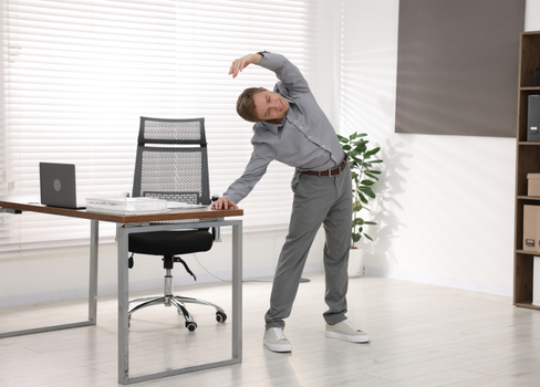 A man standing in front of a desk with his hand up.