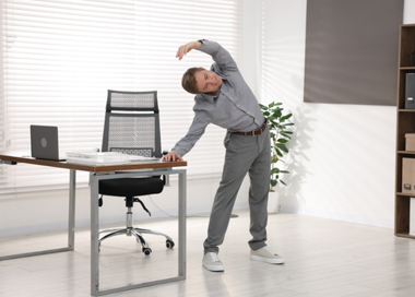 A man standing in front of a desk with his hand up.