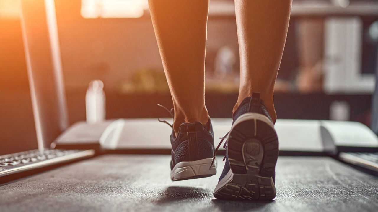 A pair of legs with a pair of shoes on a desk.