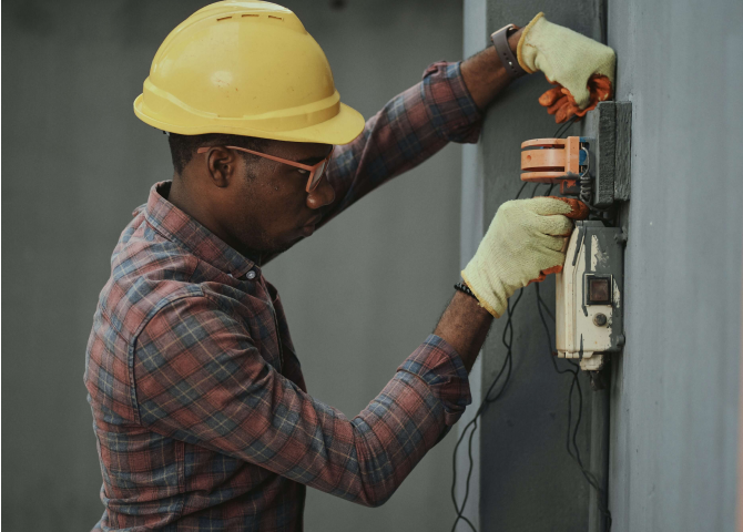 A man wearing a hard hat and holding a machine.