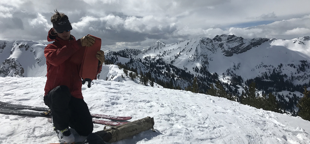 A man testing snow on a mountain.