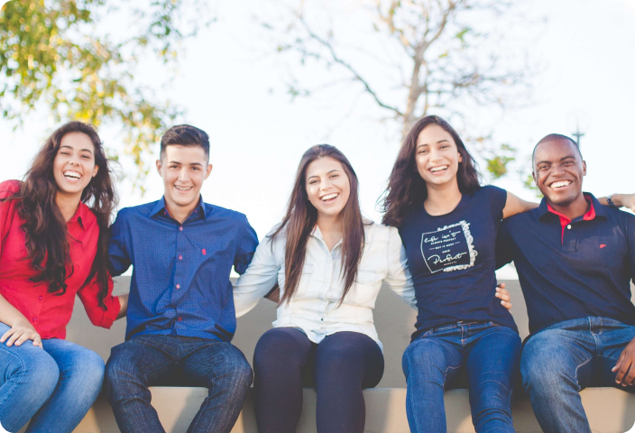 A group of young people sitting together smiling.