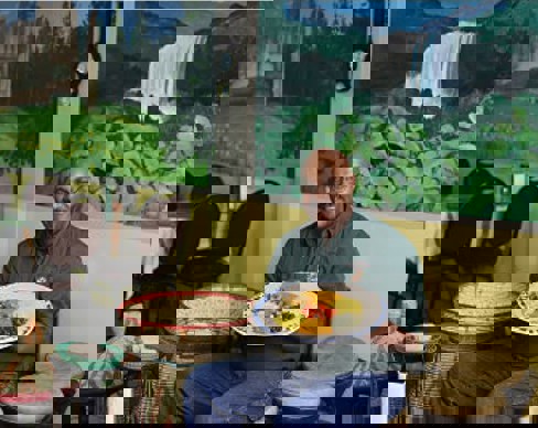 A person sitting at a table with a plate of food.