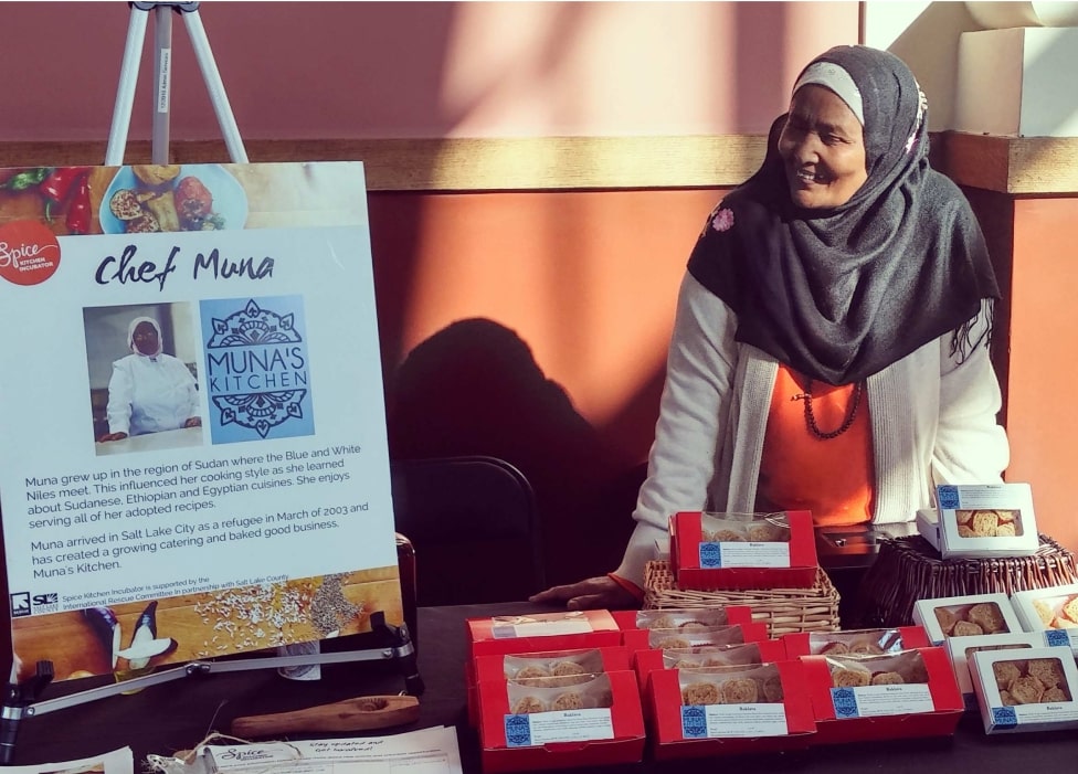 A person standing next to a table with books and a sign.