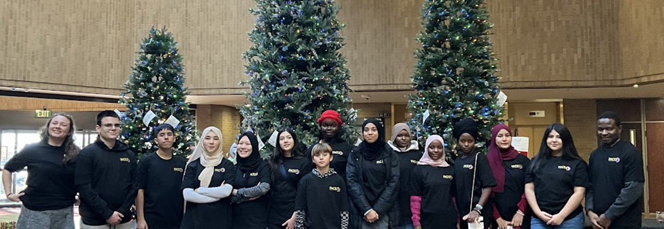 A group of people posing for a photo in front of christmas trees.