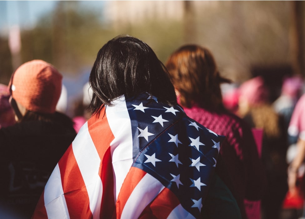 A group of people standing in a crowd holding a flag.