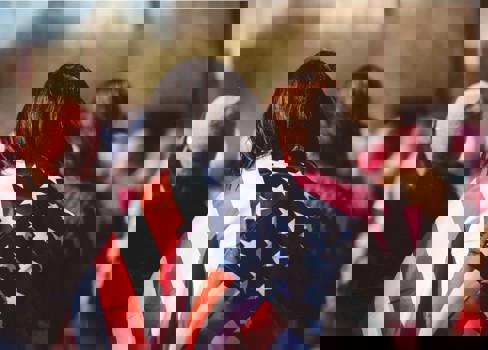 A group of people standing in a crowd holding a flag.