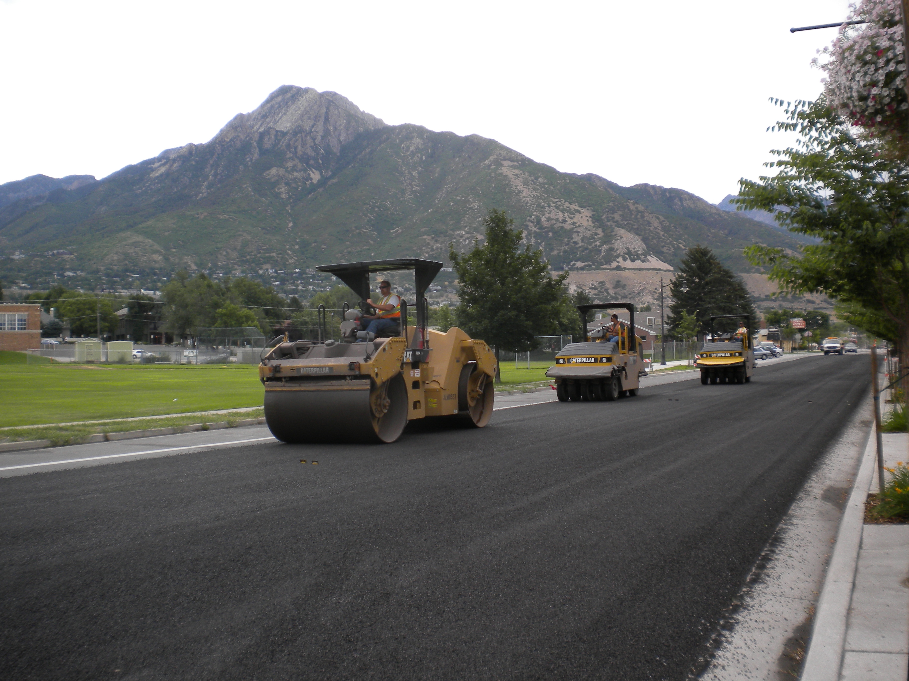 A group of vehicles driving down a road with a mountain in the background.