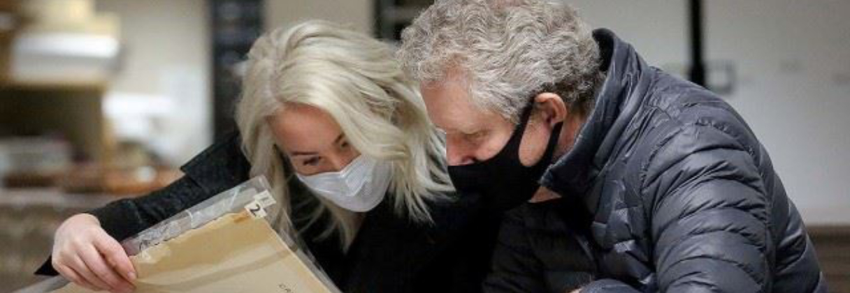 A man and woman looking at a newspaper.