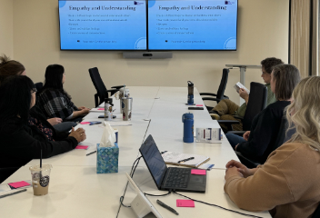 A group of people sitting at a table looking at a screen.
