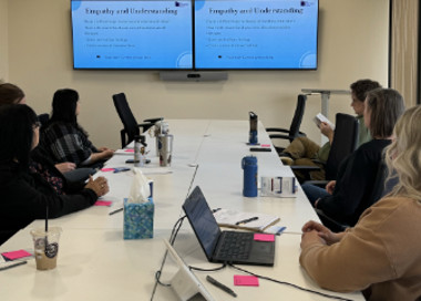 A group of people sitting at a table looking at a screen.