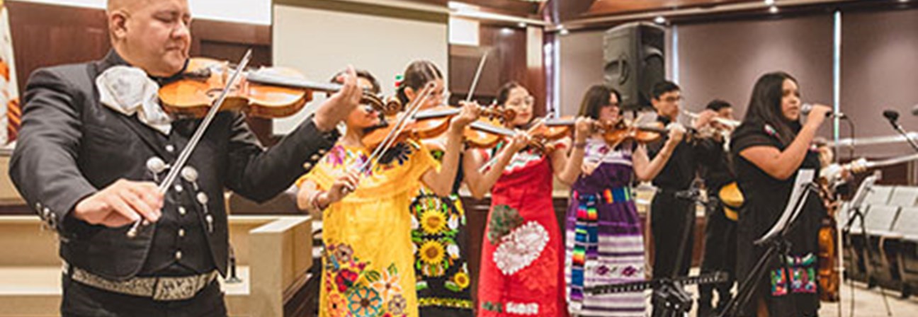 A person playing a violin in front of a group of people.