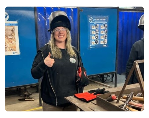 A person wearing a hat and standing next to a machine.
