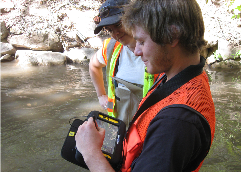 A couple of men in life jackets looking at a tablet.
