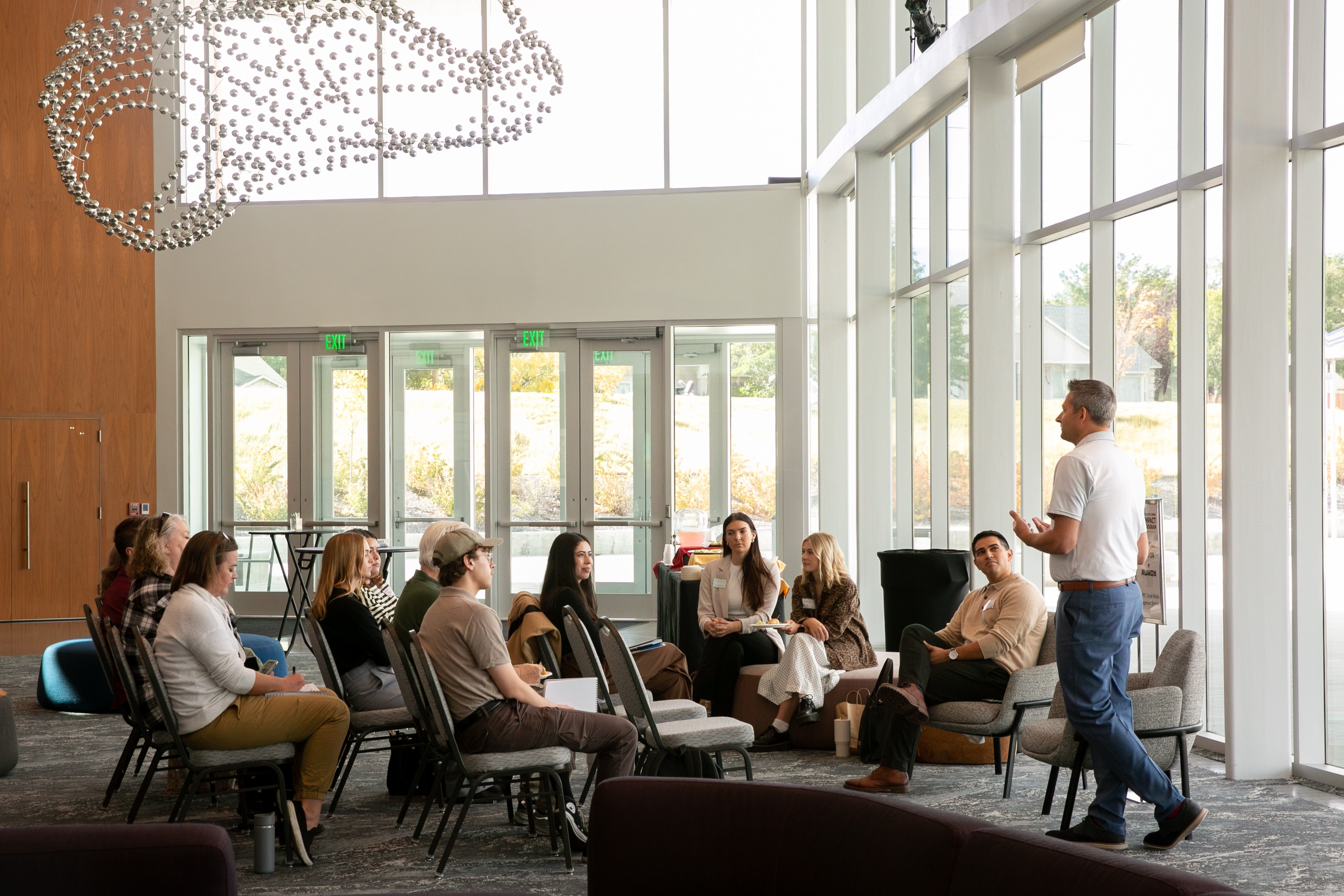 A person talking to a group of people sitting in chairs.