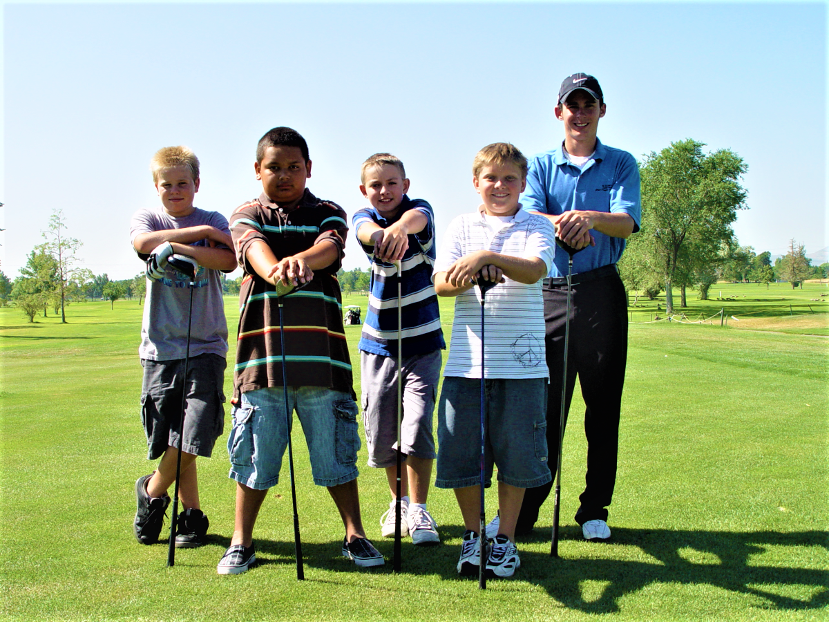 A group of boys posing for a picture on a golf course.