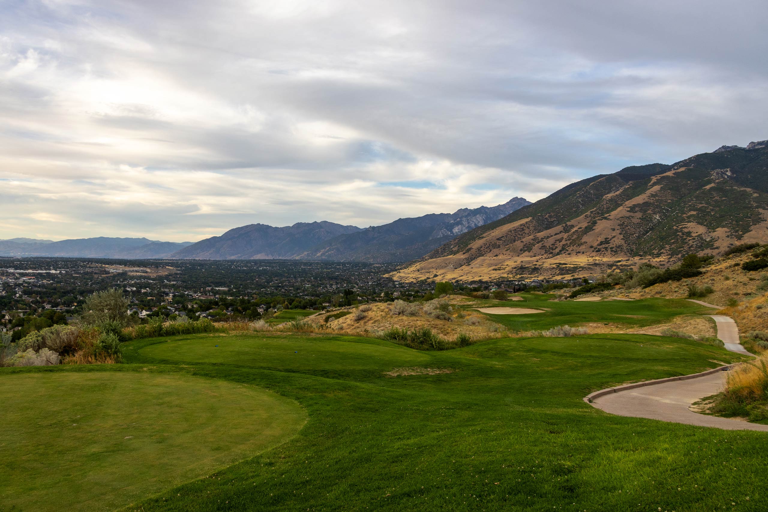A golf course with mountains in the background and a partial view of Salt Lake City neighborhoods.