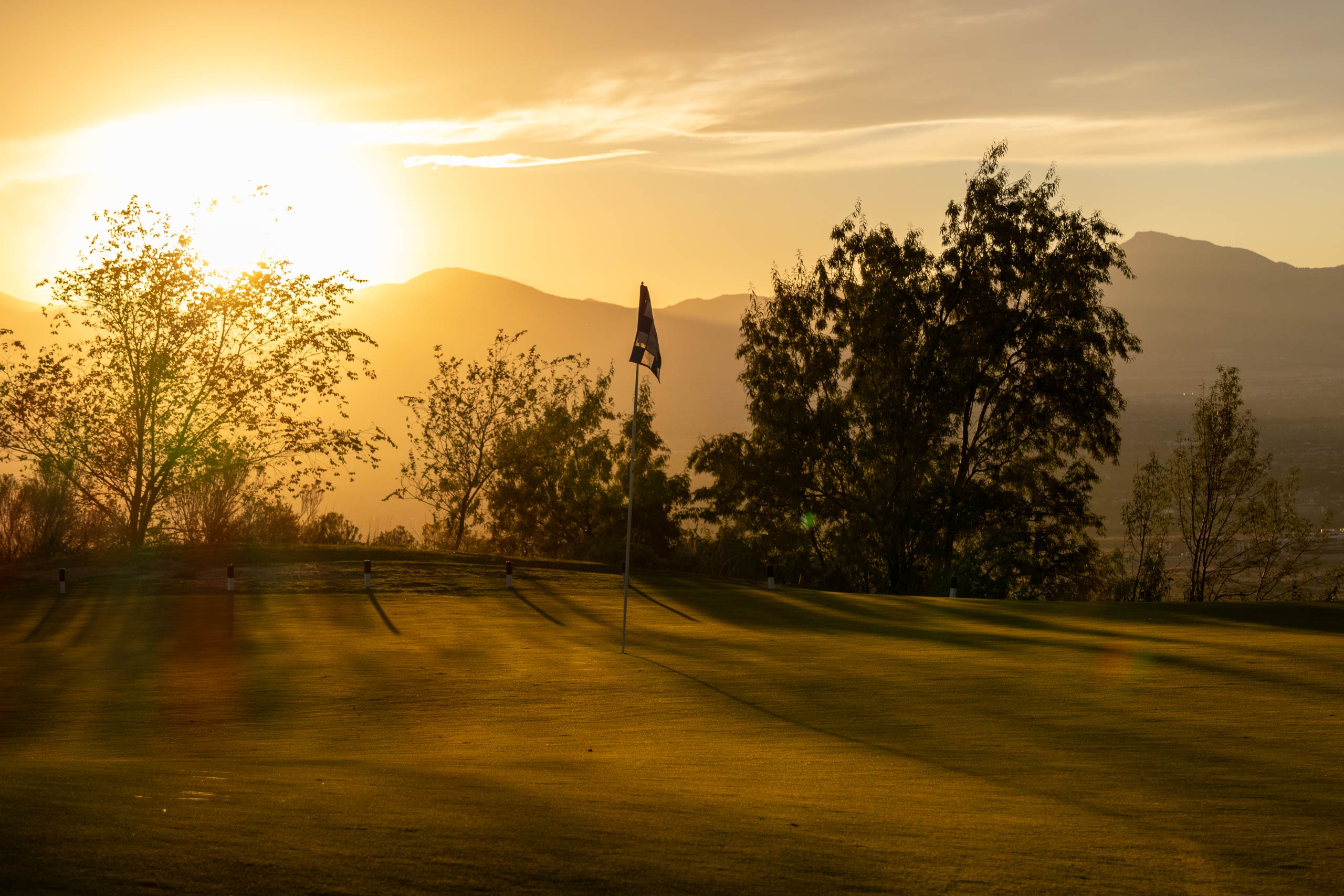 A green with flag on South Mountain golf course in Salt Lake City at sunset.
