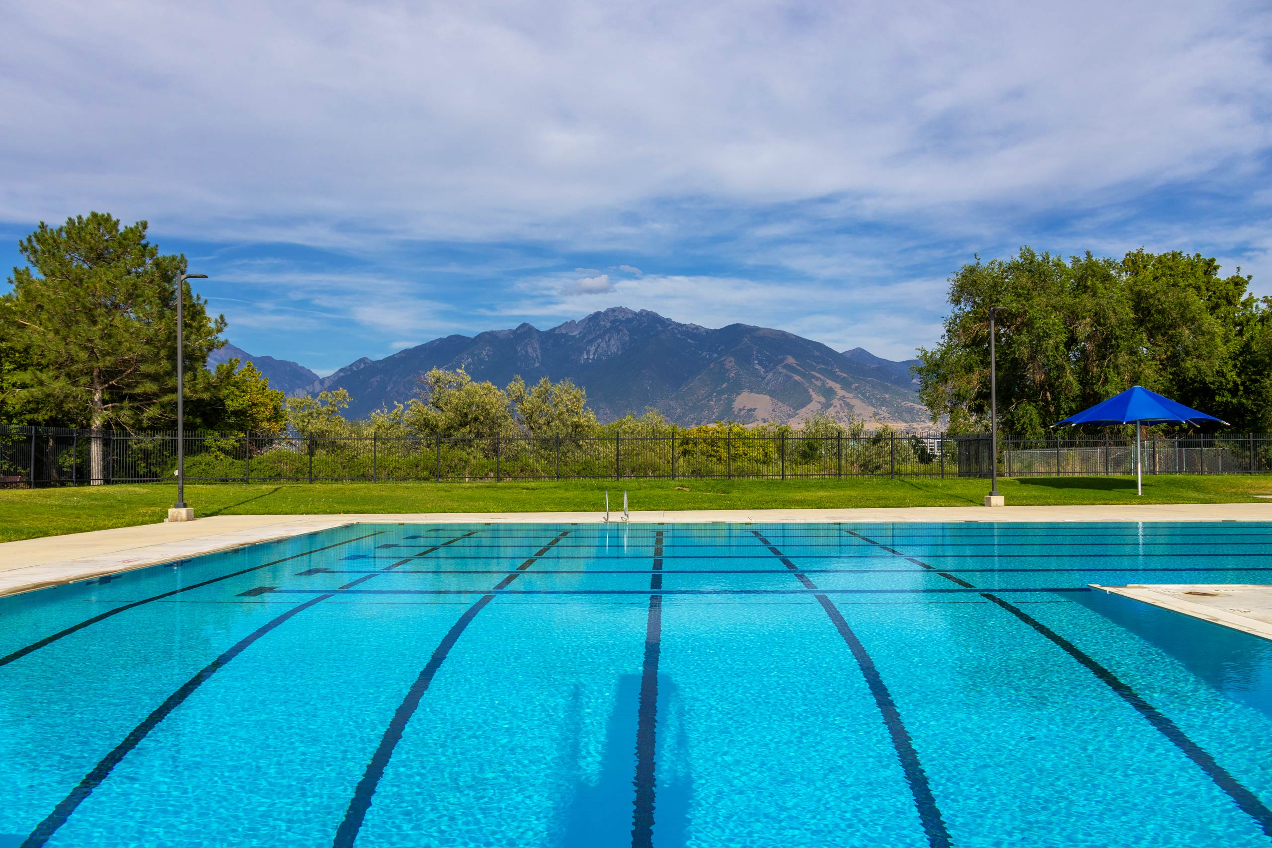 A view of the lap lanes, deep end, and mountains in the distance at South County Outdoor Pool in Riverton, Utah.