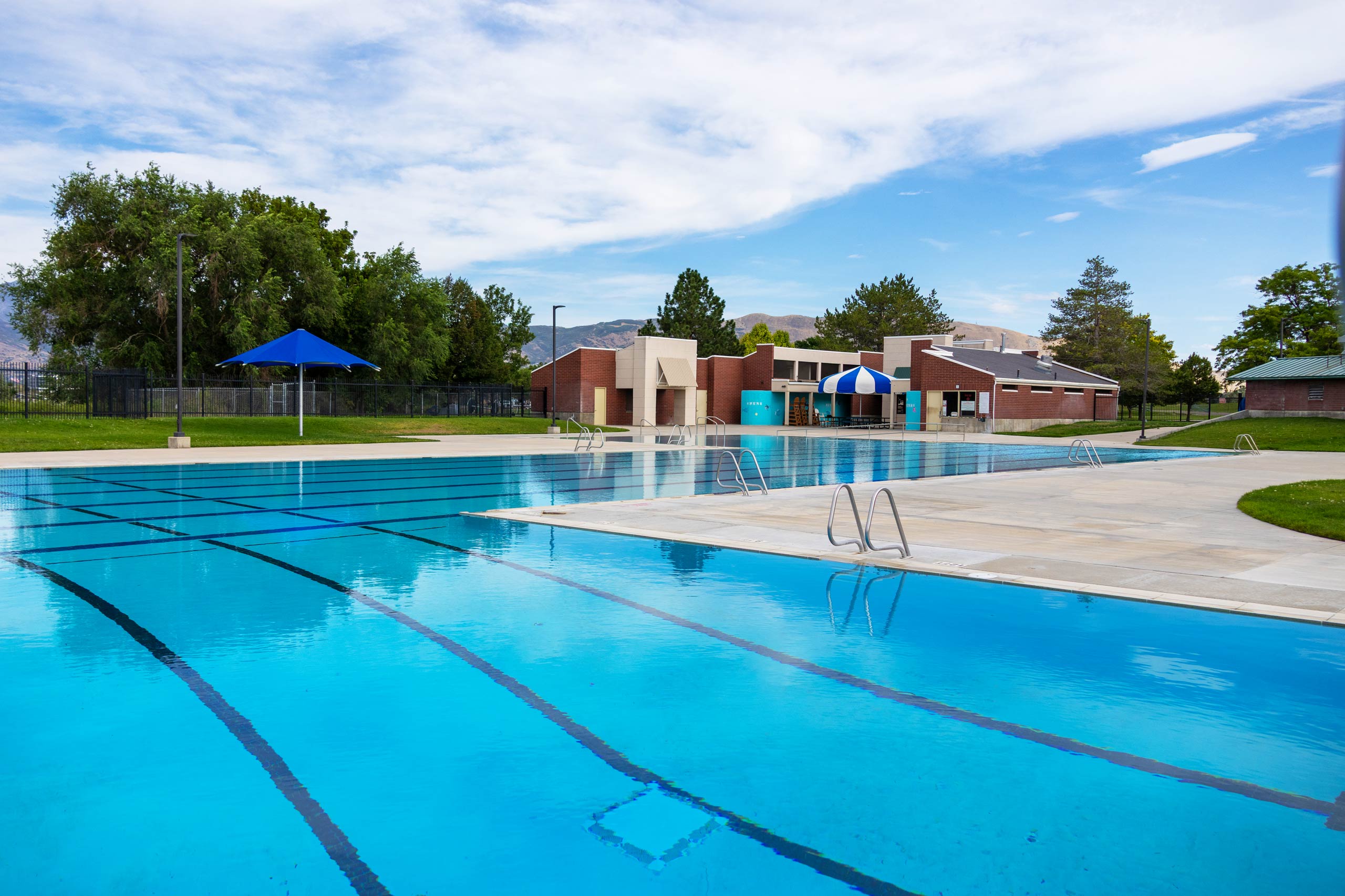 A swimming pool with a blue umbrella.