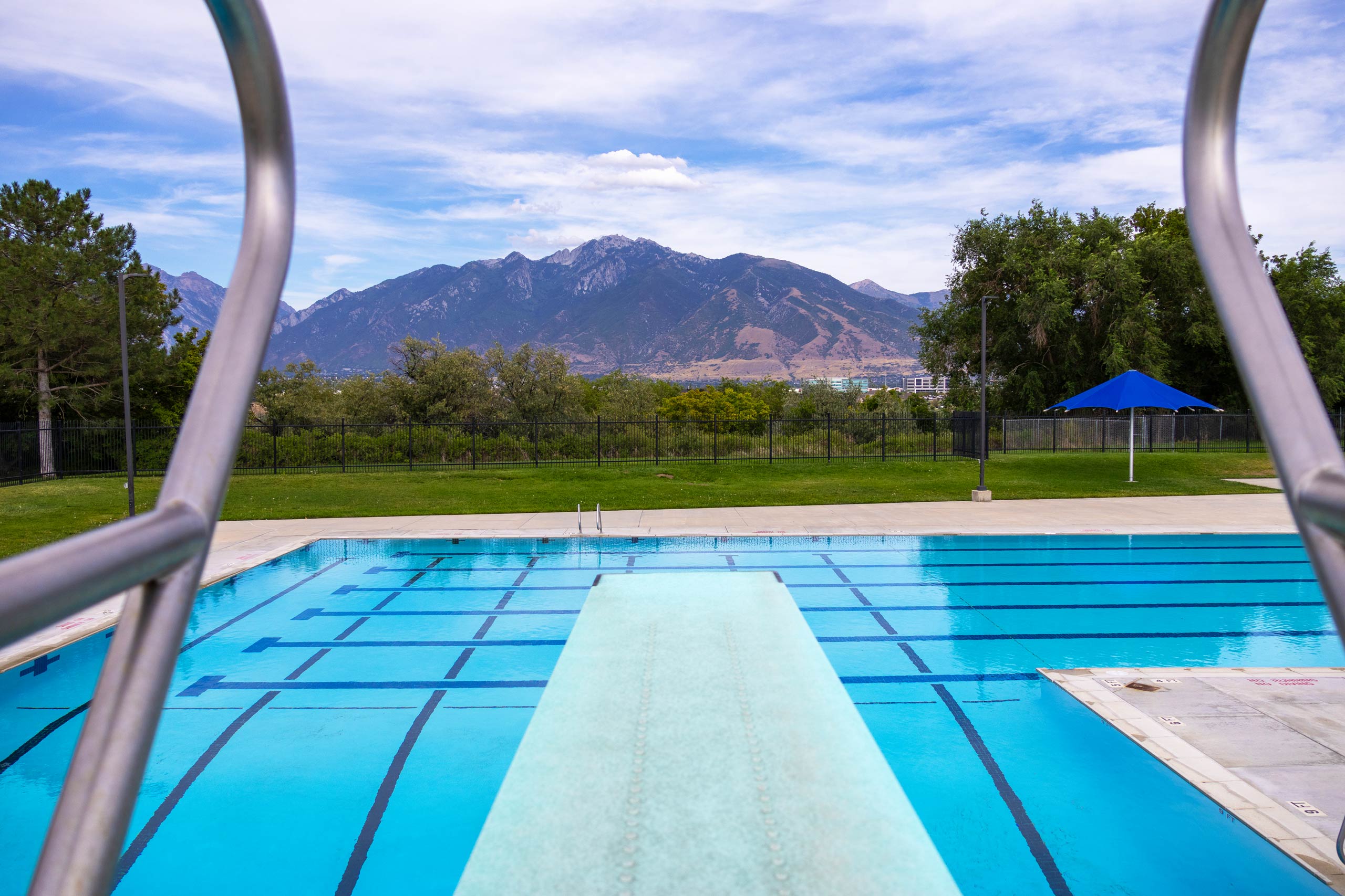 A view of the pool and mountains in the distance from the high diving board at South County Outdoor Pool in Riverton, Utah.