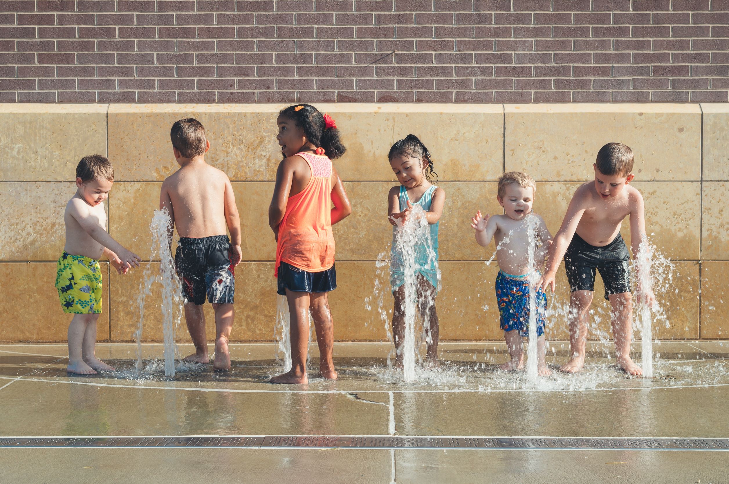 A group of children playing in a water fountain.